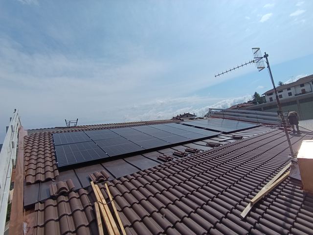 Impianto fotovoltaico su tetto in tegole, con un tecnico al lavoro in copertura
