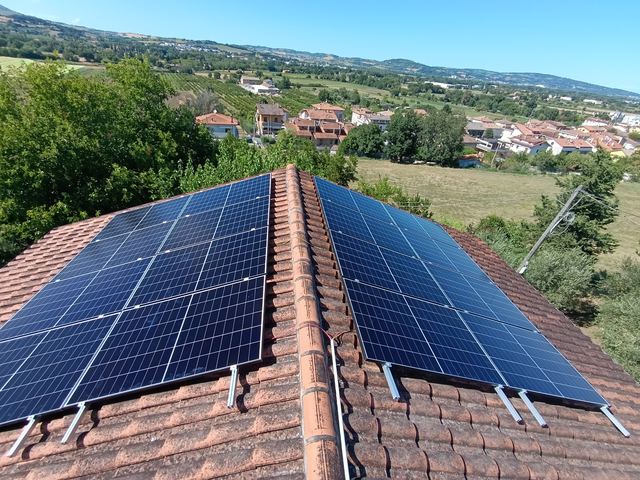 Impianto fotovoltaico su due falde di un tetto in coppi, con vista sulle colline