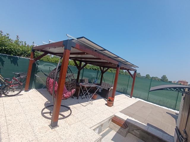 Pergola in legno con moduli fotovoltaici in copertura, su una terrazza